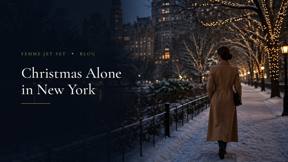 Woman in a camel coat walking alone through a snowy, lamp-lit park in New York at Christmas