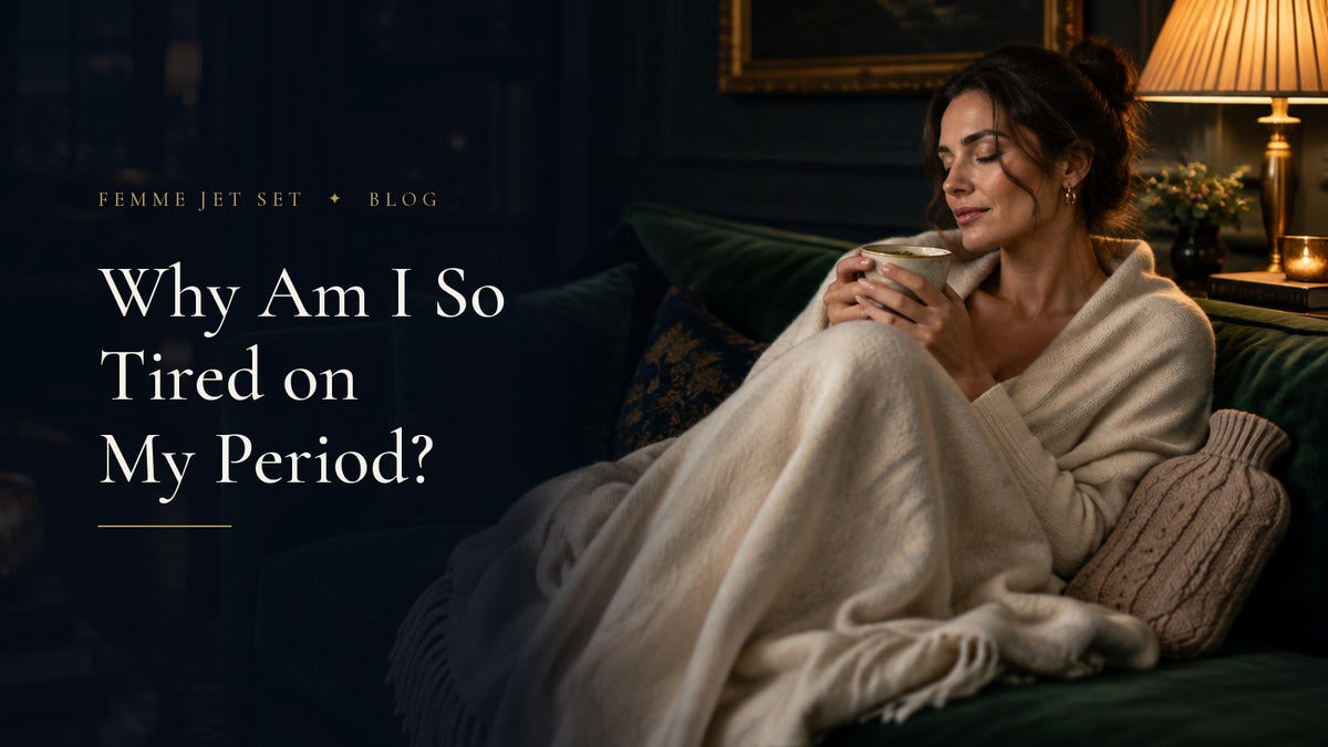 Woman resting on a green velvet sofa wrapped in an ivory cashmere throw with a cup of tea in warm lamplight, Why Am I So Tired on My Period cover